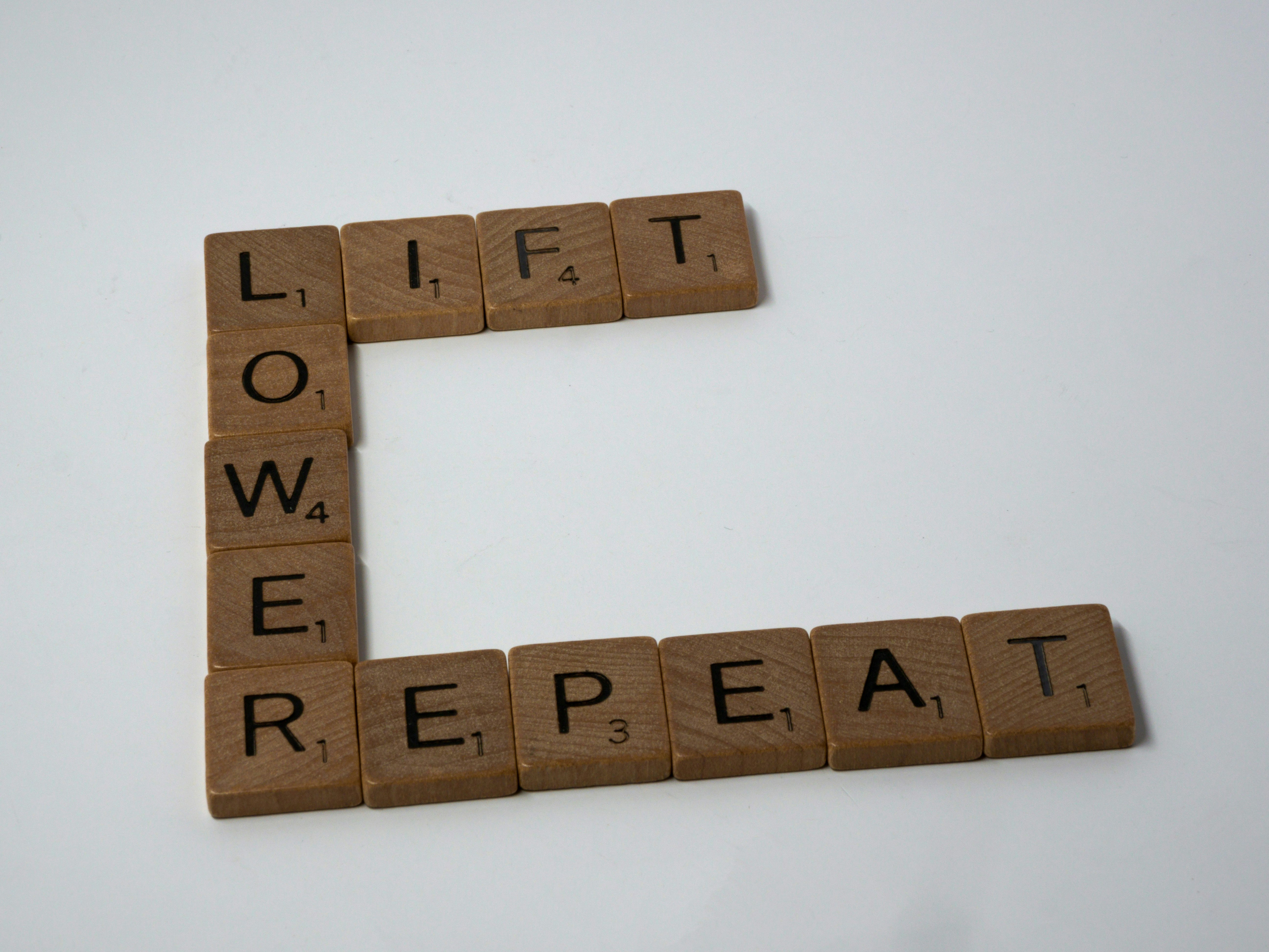 scrabble, scrabble pieces, lettering, letters, white background, wood, scrabble tiles, wood, words, lift, lower, repeat, weight training, pumping iron, fitness training, fitness, weights, barbell, dumbell, persistence, repetition, reps,
